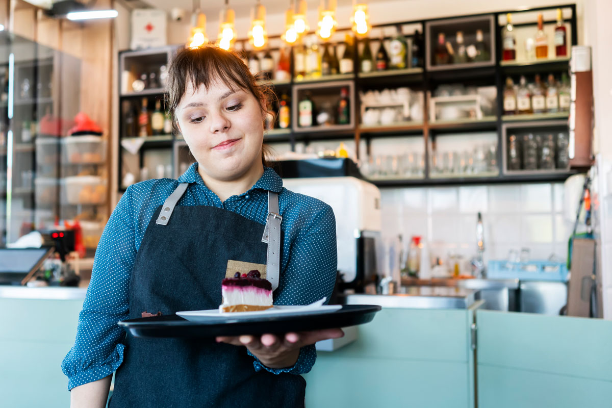 Eine junge Frau serviert ein Stück Kuchen in einem Café