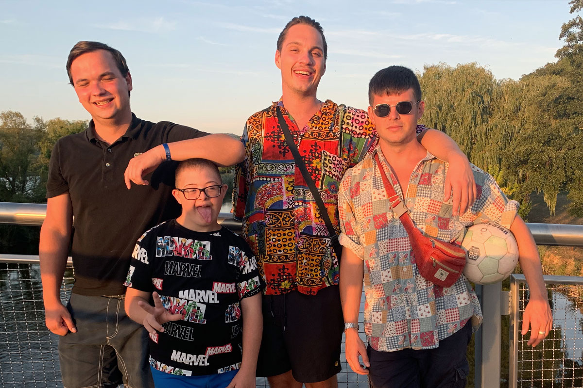 Vier Personen stehen auf einer Brücke und machen ein Foto bei Sonnenuntergang. 